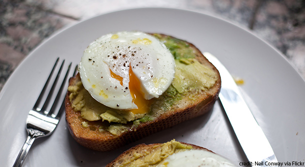 Smashed avocadoes topped with over-easy eggs on toast